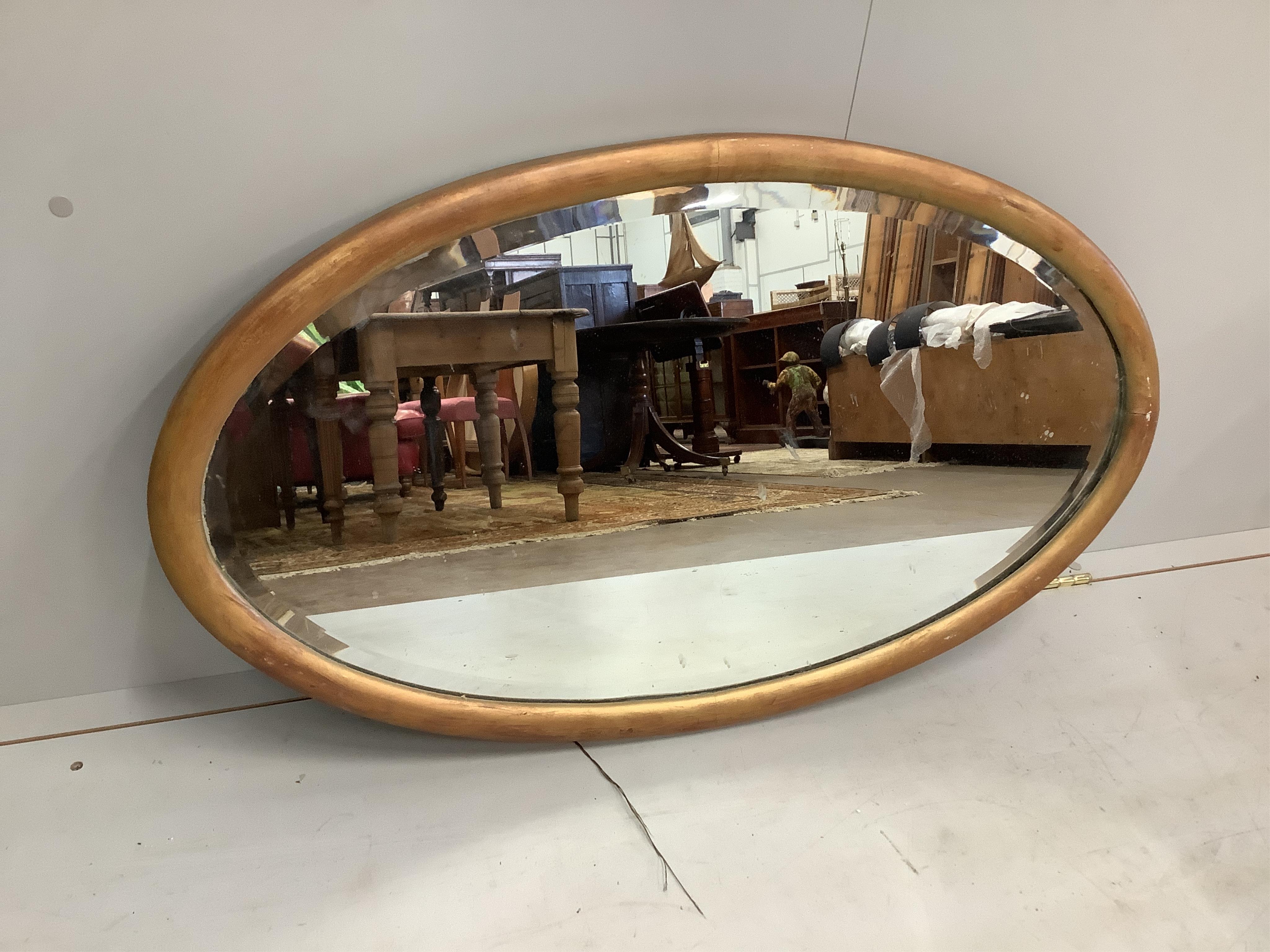 An Edwardian oak pierced frame mirror and an oval wall mirror, larger width 64cm, height 85cm